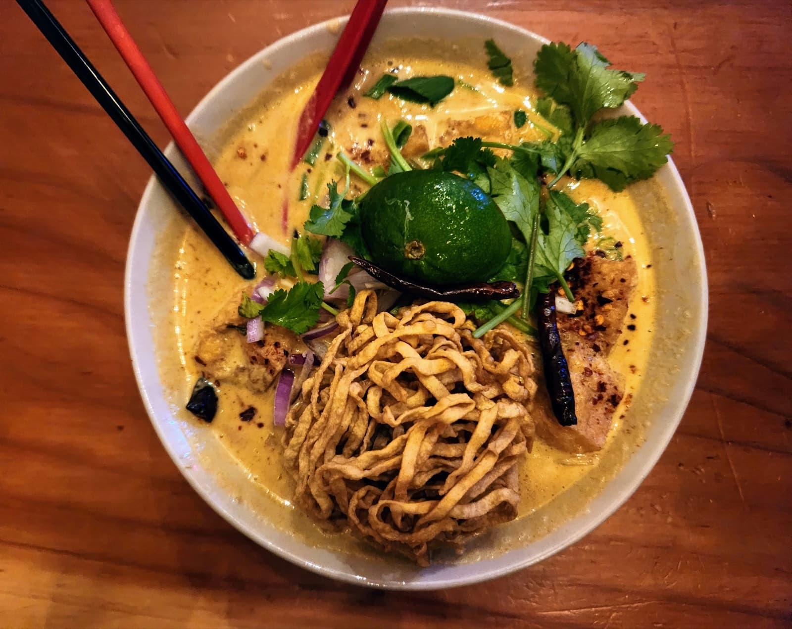 A bowl of coconut curry noodles with lime and fresh herbs